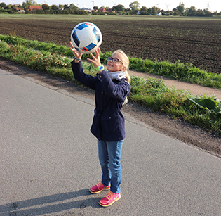 Kind spielt Ball mit einem GPS Tracker am Handgelenk